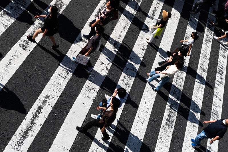 横断歩道の縞模様に映る人影の写真