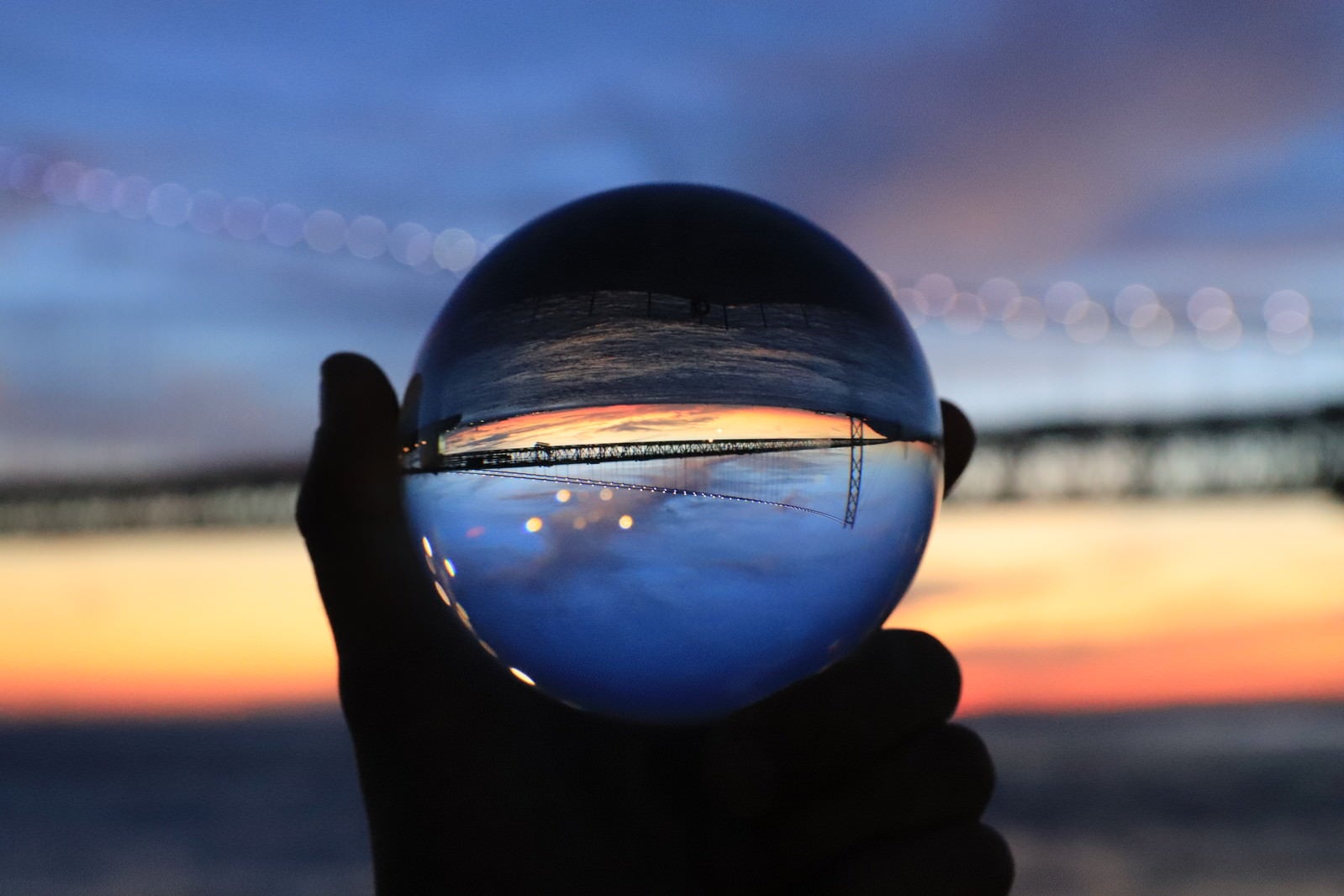 「ガラス玉越しに見た夕焼けと橋」の写真