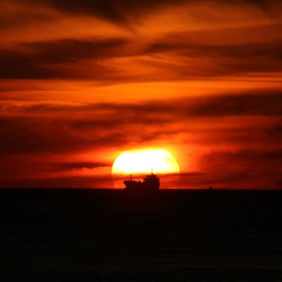 夕日に染まる空と貨物船のシルエットの写真