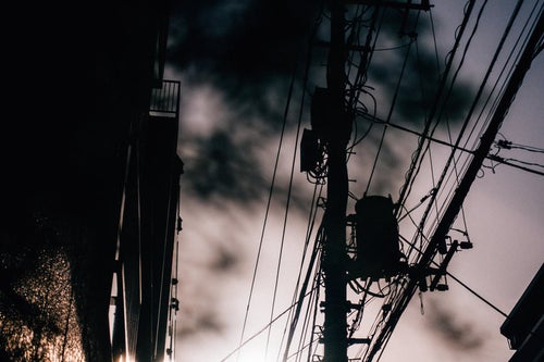 曇り空に映える不穏な電柱と電線の風景の写真