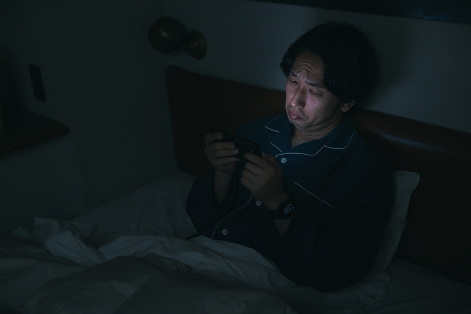 「眠れなくてスマホで動画を見てしまう男性」の写真［モデル：大川竜弥］