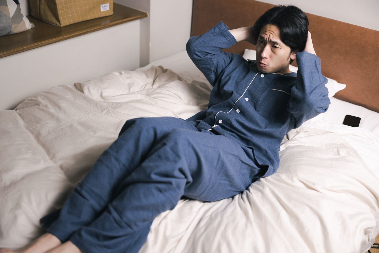 「ベッドの上で腹筋をはじめる男性」の写真［モデル：大川竜弥］