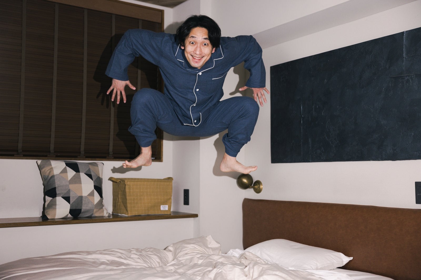 「目覚めのよさに驚きベッドの上でジャンプをしてしまった男性」の写真［モデル：大川竜弥］