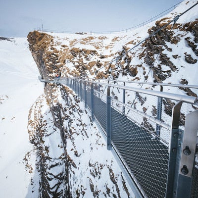 断崖雪壁に設置された吊橋の様子（スイス）の写真