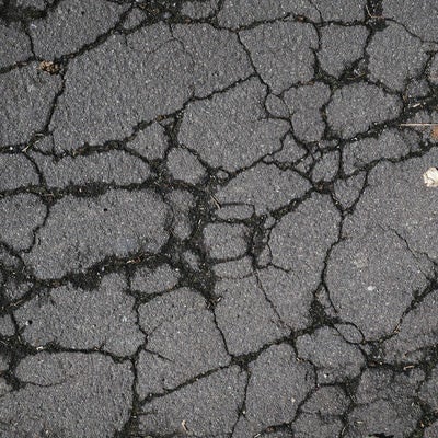 アスファルトの地面に入ったヒビ（テクスチャー）の写真