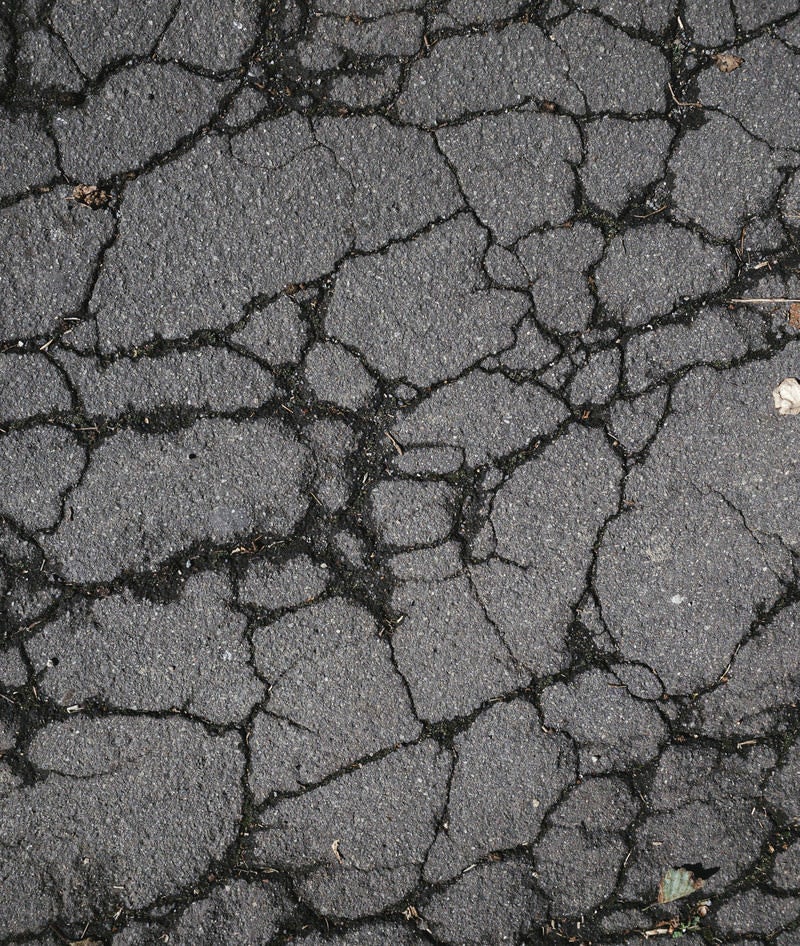 アスファルトの地面に入ったヒビ（テクスチャー）の写真