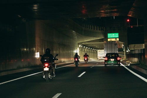 夜間走行するバイクと自動車の写真