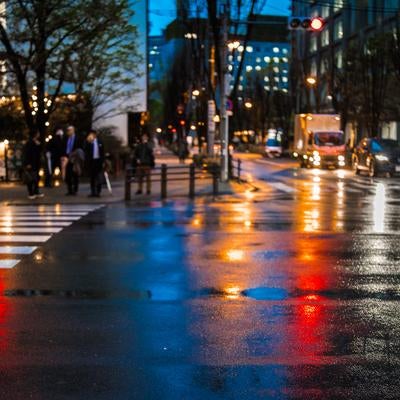 雨上がりの横断歩道に映る信号の灯りの写真