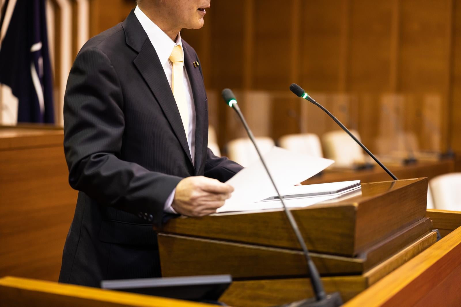 「資料を手にした演壇での発言者」の写真