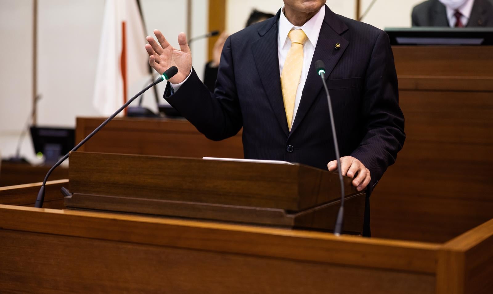「津山市議会の本会議場で熱弁を振るう男性議員の演説シーン」の写真