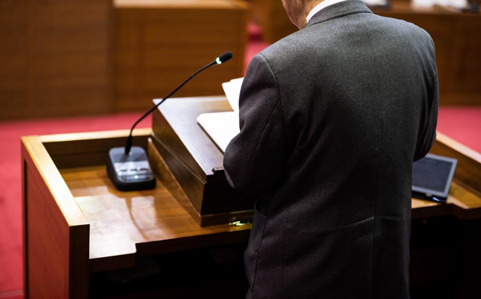 「議会の演壇に立つ政治家の後ろ姿」の写真