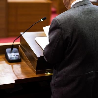 議会の演壇に立つ政治家の後ろ姿の写真