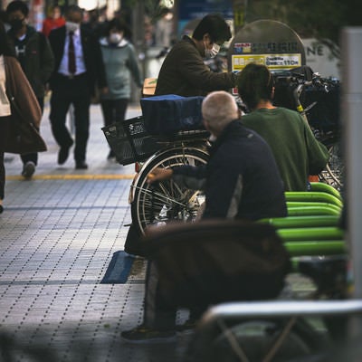 新宿の歩道脇にある駐輪場とベンチに座る人たちの写真