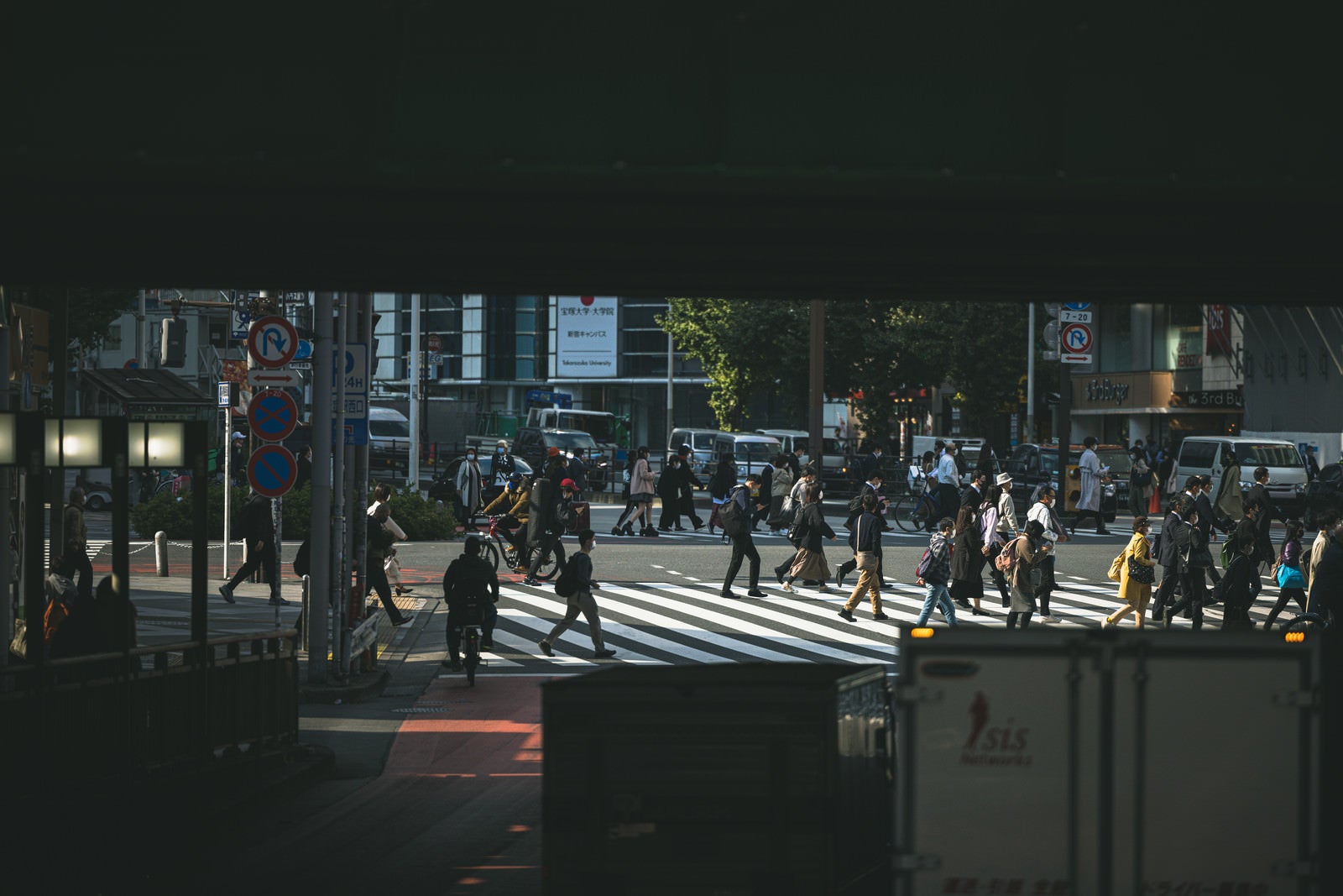 「高架下から見る横断歩道を渡る人混み」の写真