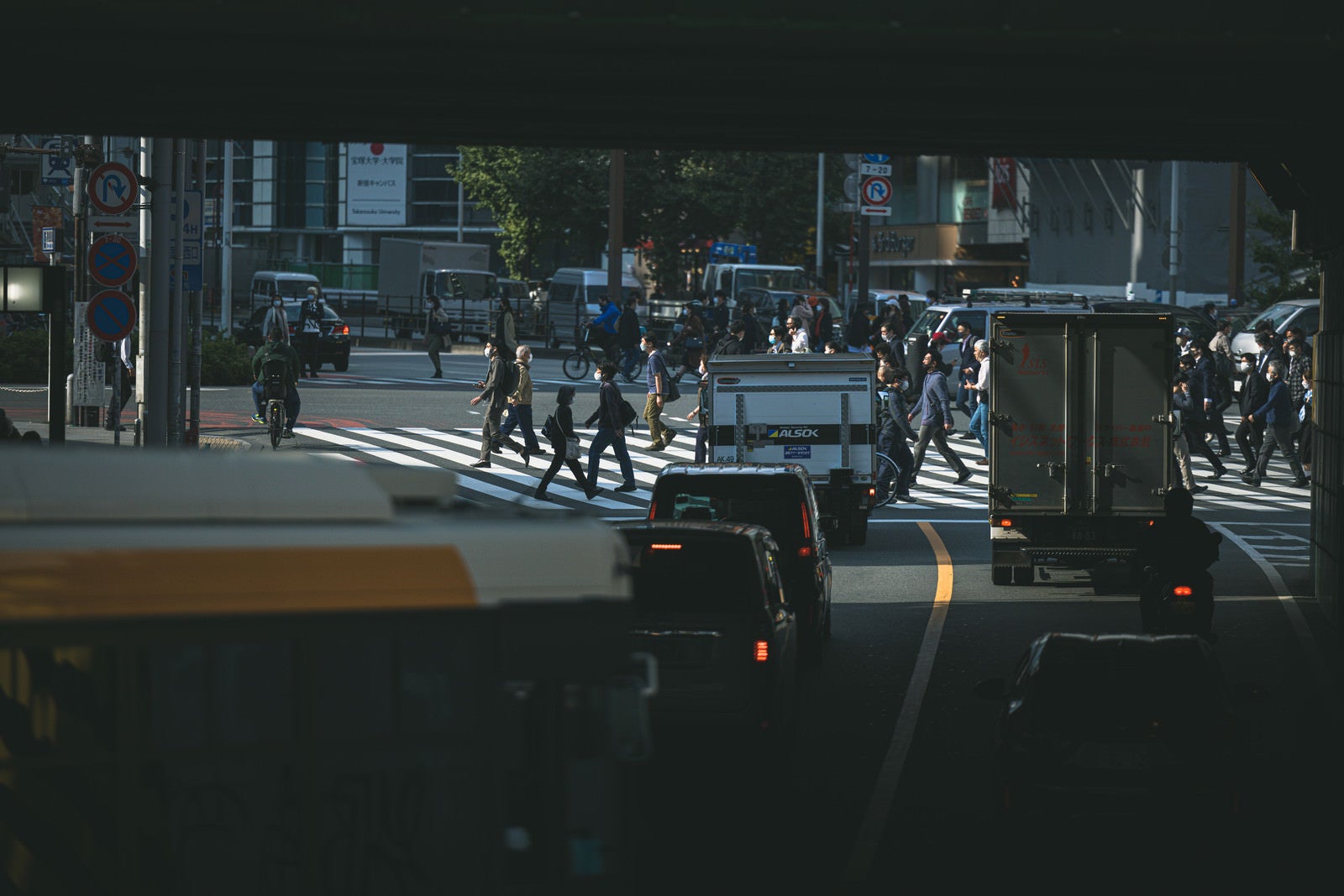 「号待ちする車両と横断する歩行者」の写真