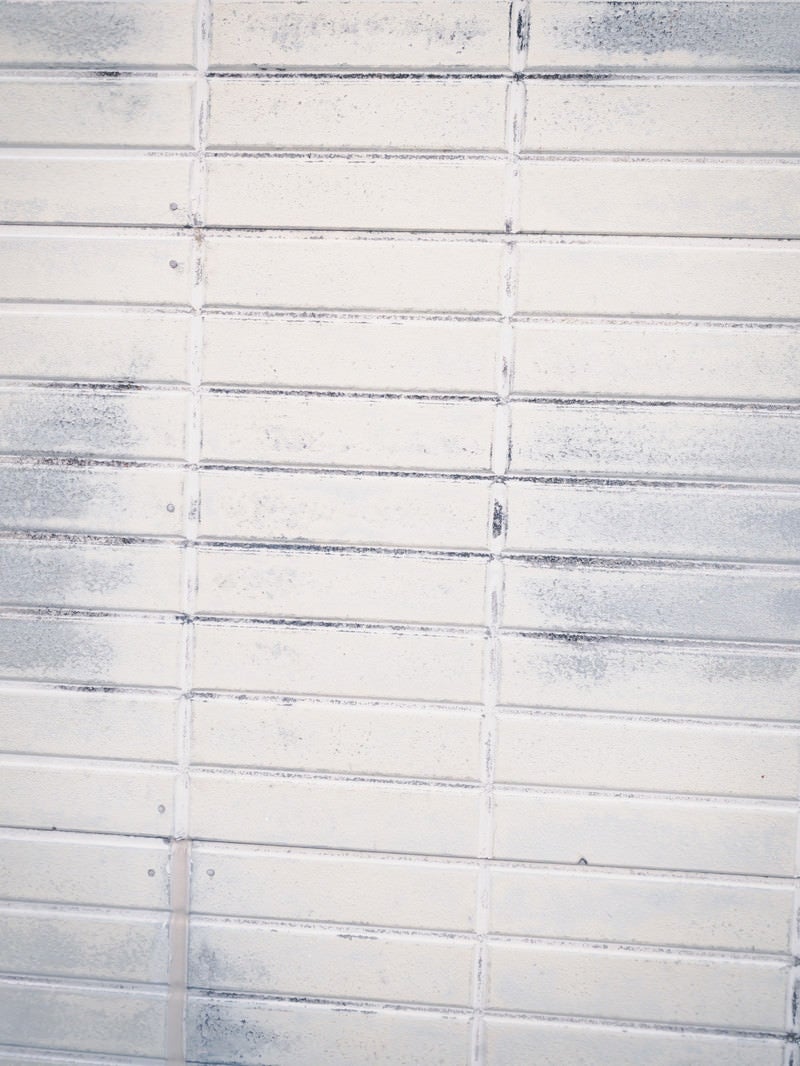「擦れ跡残るホワイト色のタイル壁（テクスチャ）」の写真