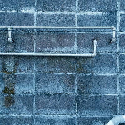 ブロック塀からのびる配管の写真