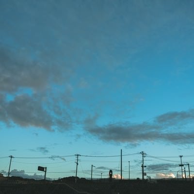 電柱のシルエットと薄雲かかる青空の写真