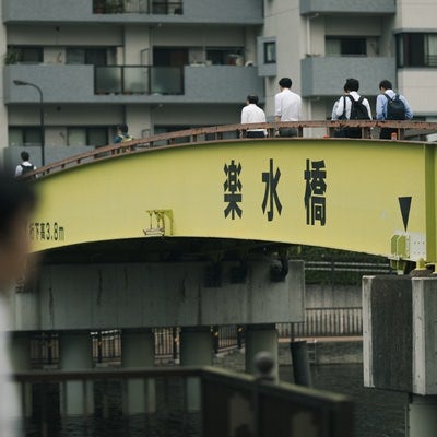 黄色い楽水橋を渡る人たちの写真