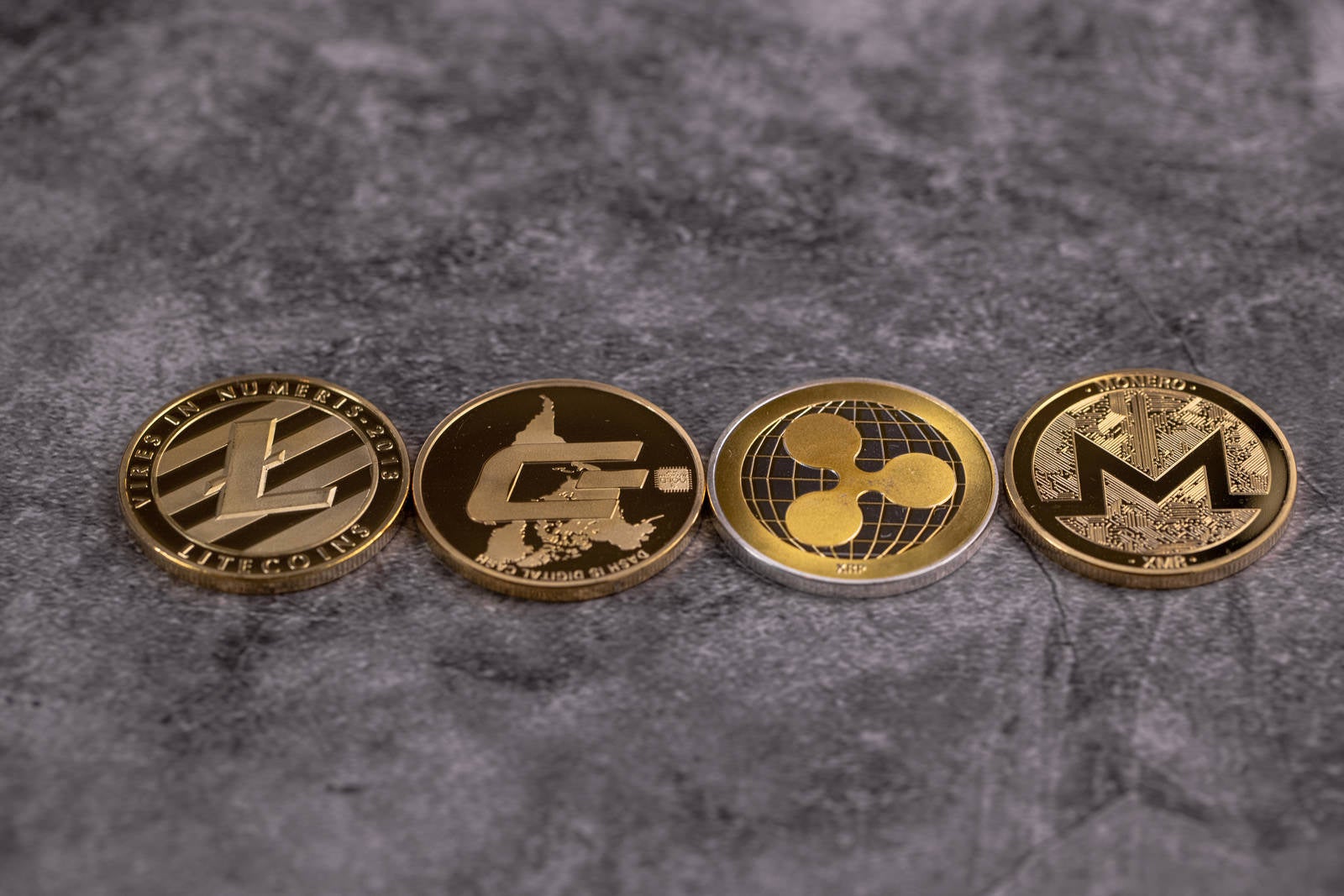 「整列した四枚の金貨（LTC,DASH, XRP, XMR）」の写真
