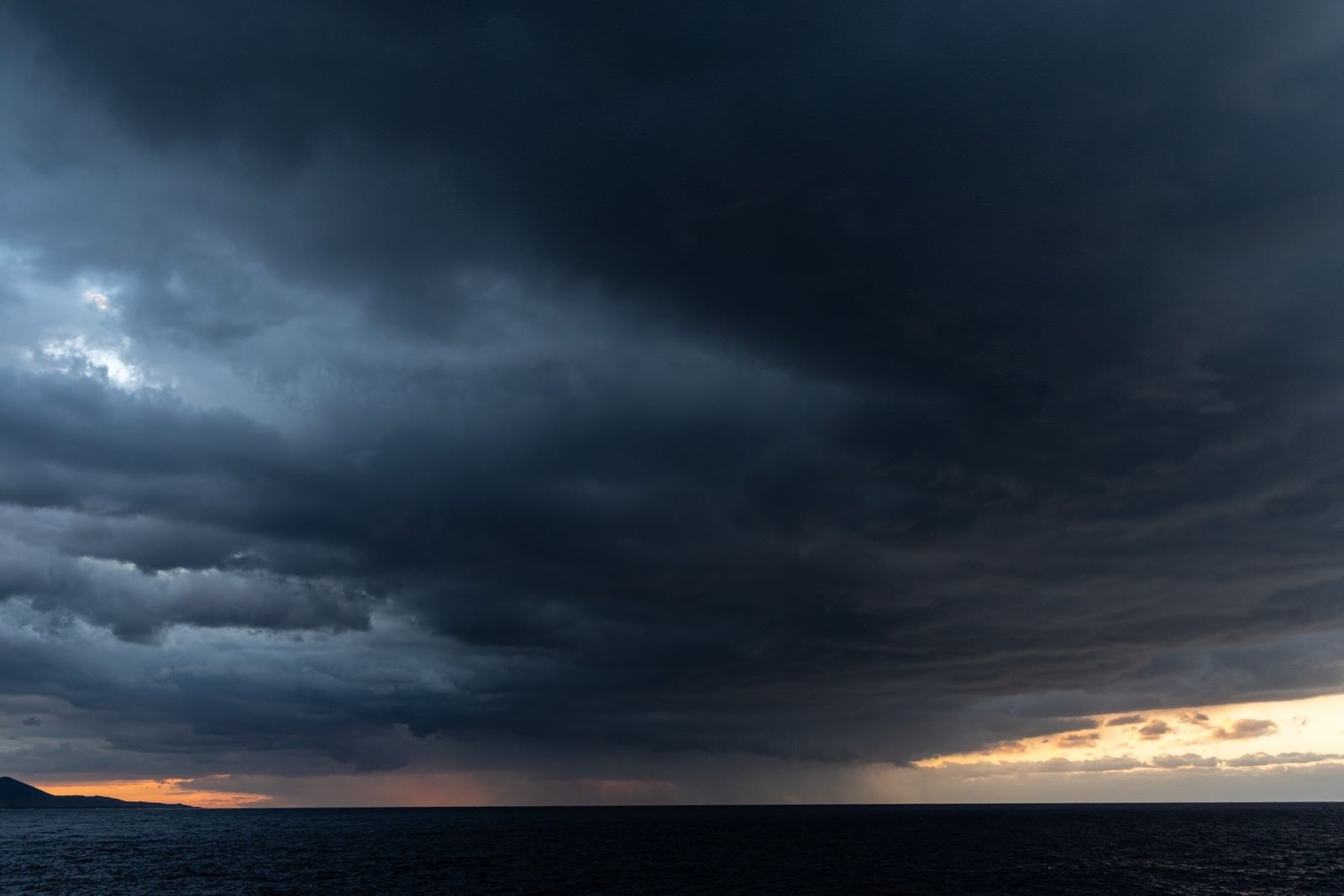 「夕焼け空を覆い尽くす黒い雲」の写真