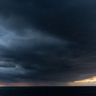 夕焼け空を覆い尽くす黒い雲の写真