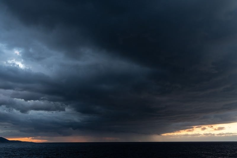 夕焼け空を覆い尽くす黒い雲の写真