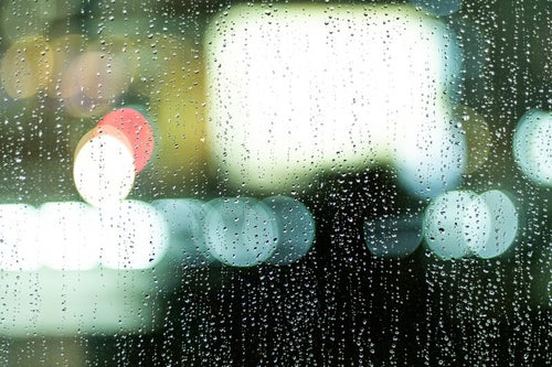 煌めくネオンと雨粒残る窓ガラスの写真