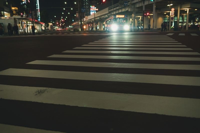 バスのヘッドライトと横断歩道の白線の写真