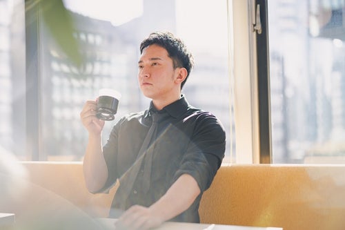 コーヒーで一息入れる経営者の男性の様子の写真