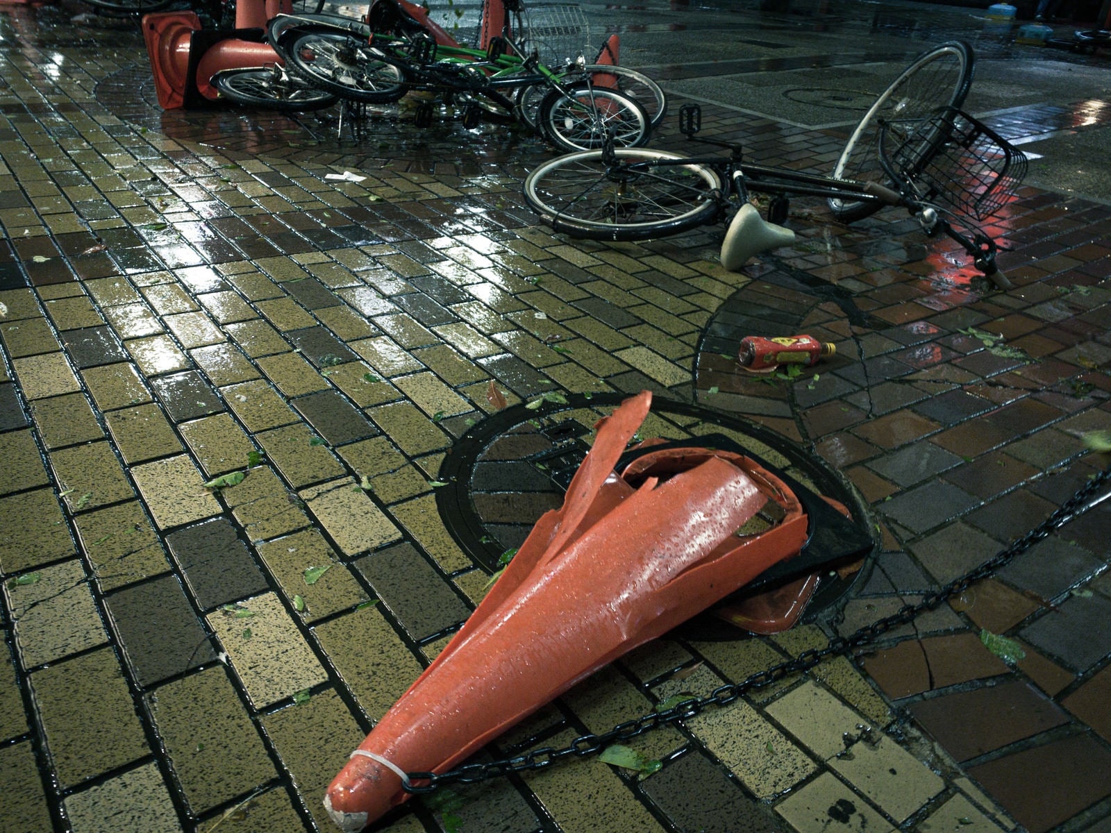 「大型の台風の後、なぎ倒されたカラーコーンと自転車」の写真