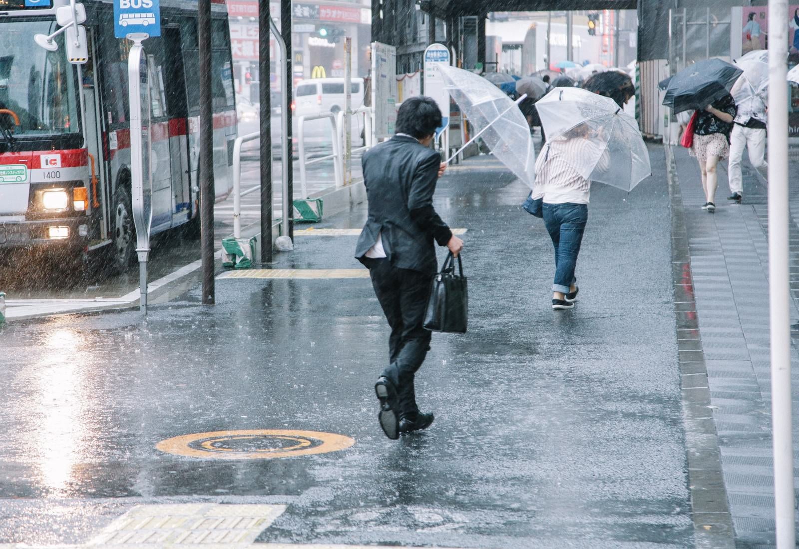 「大雨と強風の中、出社する社畜ビジネスマン（びしょ濡れ）」の写真