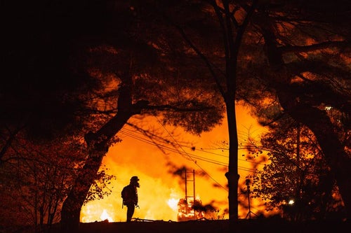 松明あかしの炎と消防士のシルエットの写真