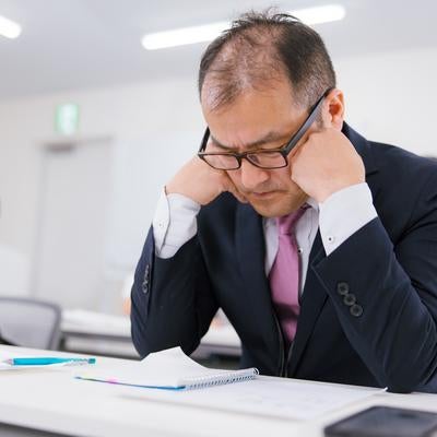 会議中に疲労感で居眠りそうな管理職の男性の写真