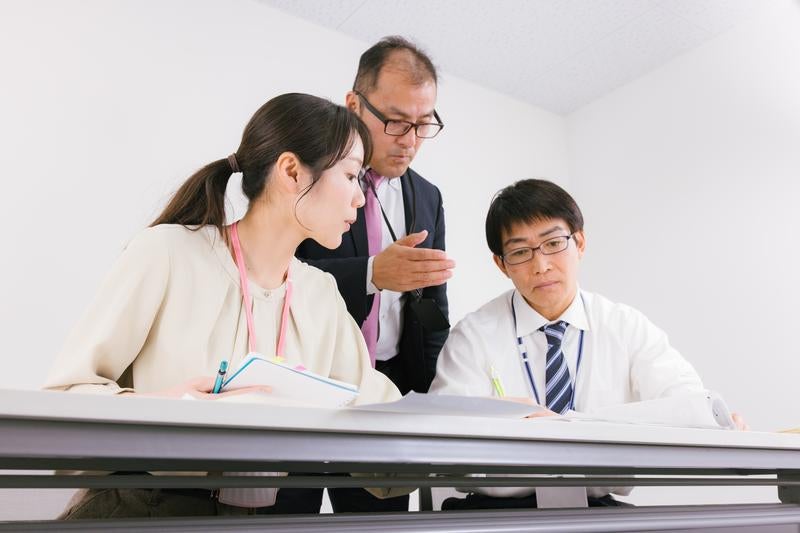 真剣な表情で打ち合わせする三人の会社員の写真