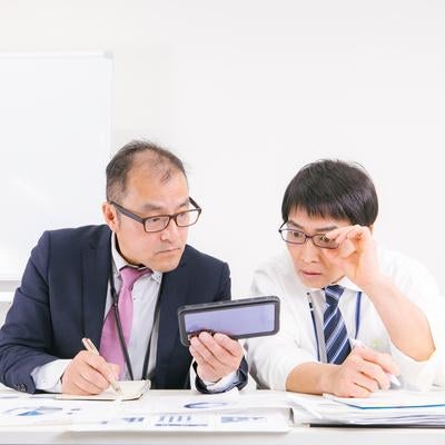 会議室で熱心に話し合える2人の男性社員の写真