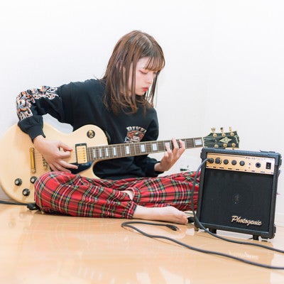 部屋でギターを練習する彼女の写真