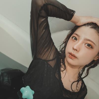 リラックスした表情で髪をかきあげる湯上がり女性の写真