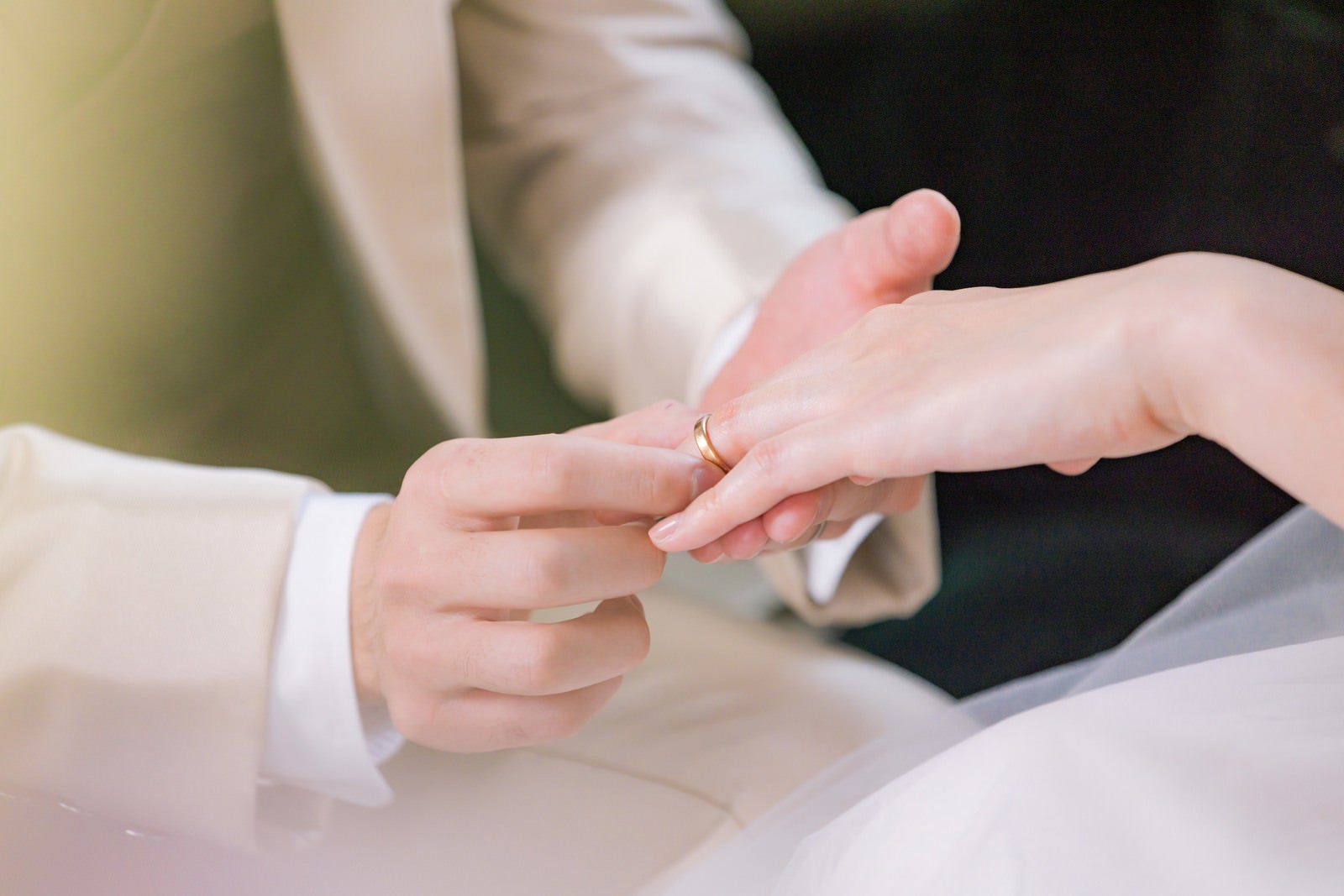 「新婦の左の薬指に結婚指輪をつける様子」の写真［モデル：たけべともこ］