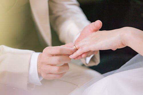 新婦の左の薬指に結婚指輪をつける様子の写真
