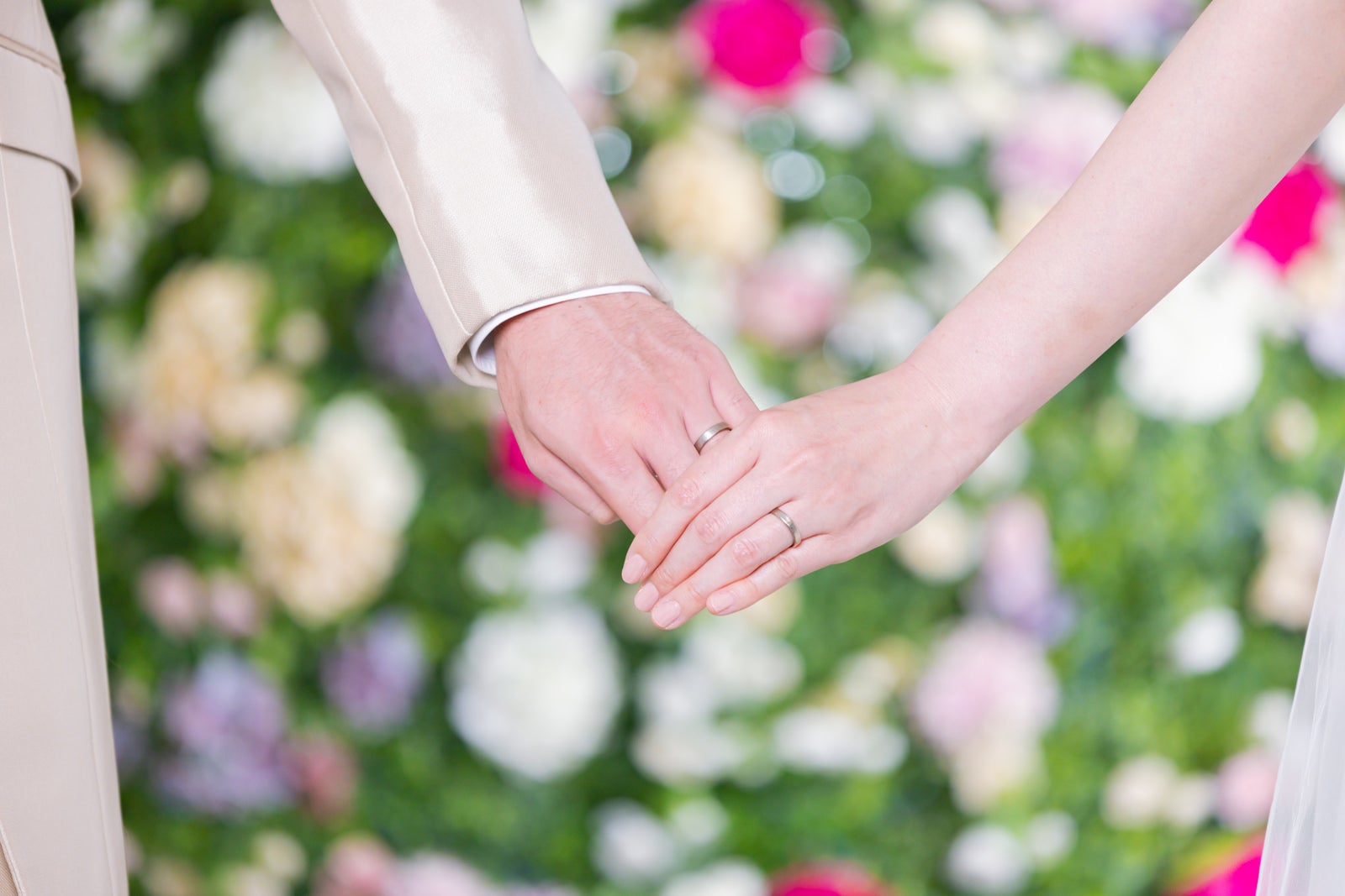 「結婚指輪を見えるように手を握り合う新郎新婦」の写真［モデル：たけべともこ］