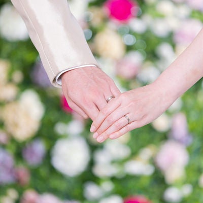 結婚指輪を見えるように手を握り合う新郎新婦の写真