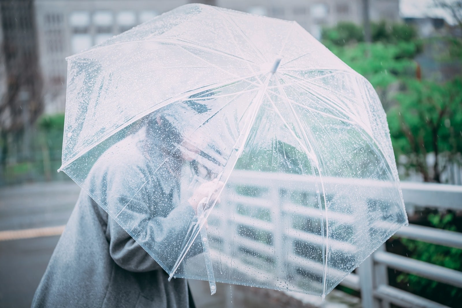 「ビニール傘を盾に進む女性」の写真［モデル：たけべともこ］
