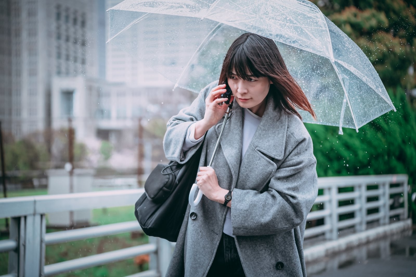 「傘を差しながら通話する女性」の写真［モデル：たけべともこ］