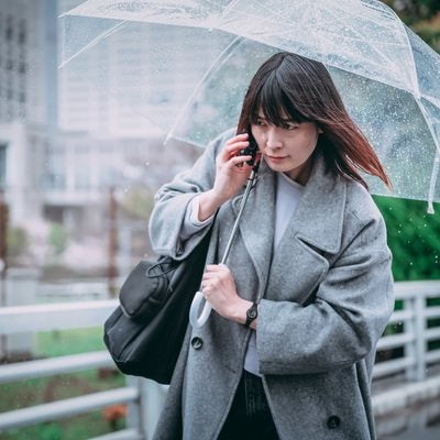 傘を差しながら通話する女性の写真