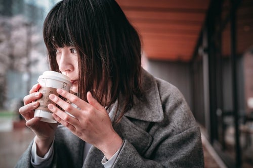 ホットコーヒーを啜る女性の写真