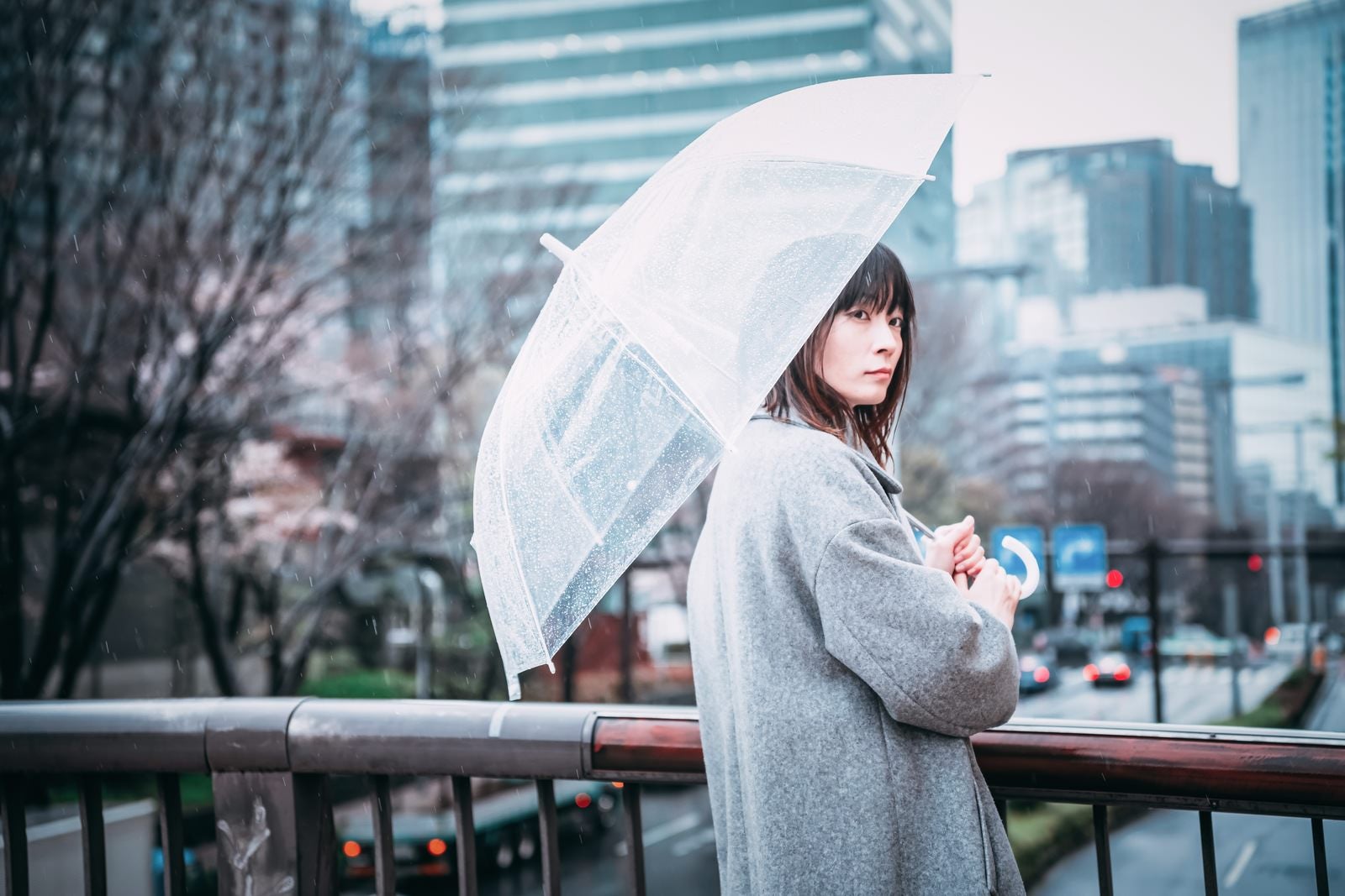 「ビニール傘を差して待ち合わせする女性」の写真［モデル：たけべともこ］