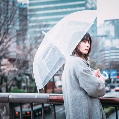 ビニール傘を差して待ち合わせする女性の写真