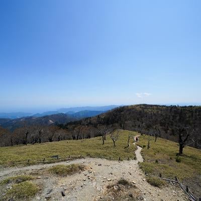 登山道の先に広がる稜線と遠くに見える青い海の写真