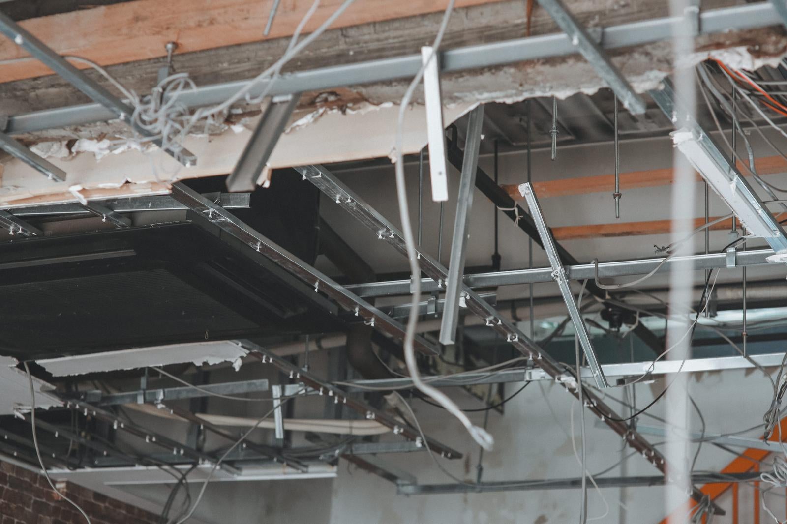 天井が崩落し金属フレームと白い配線が露出した室内